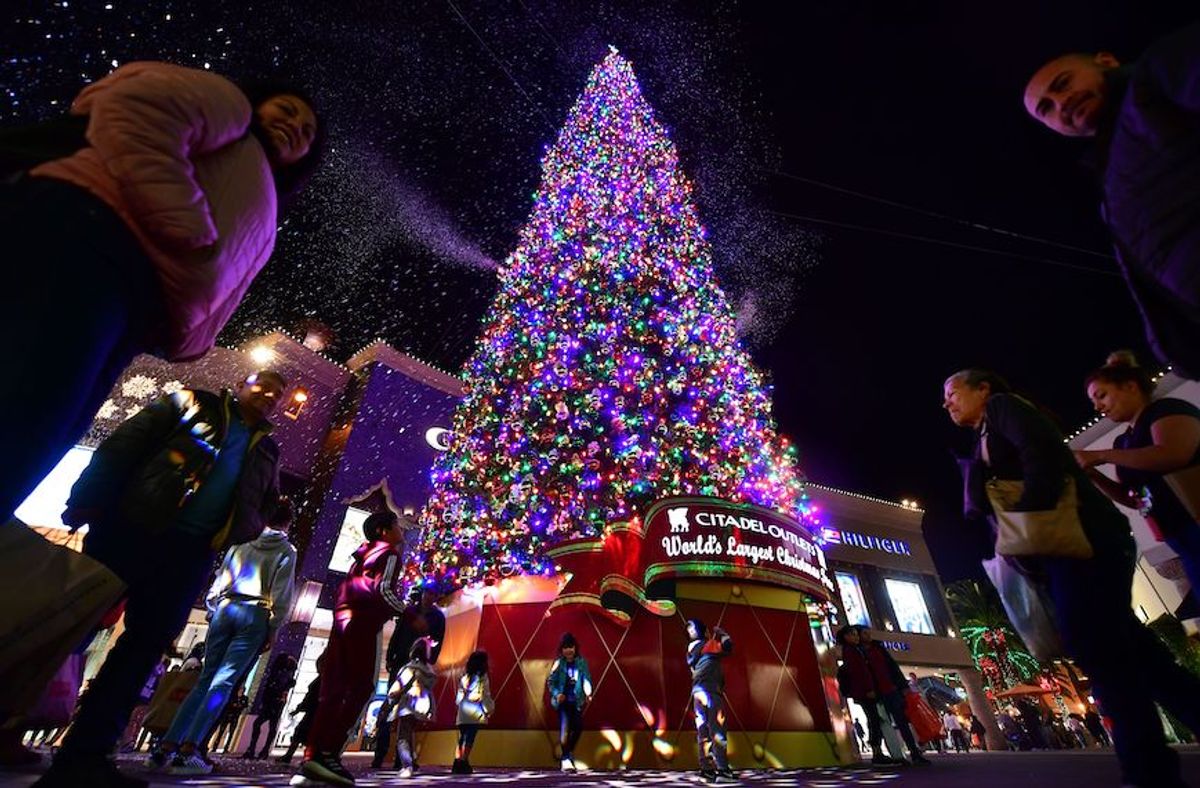 Children get excited by the artificial snow spewing from the "World's Tallest live-cut Christmas Tree," standing 115 feet and decorated with some 18,000 multi-colored LED lights, at the Citadel Outlets shopping plaza in Los Angeles, California on December 17, 2019. (Photo by Frederic J. BROWN / AFP) (Photo by FREDERIC J. BROWN/AFP via Getty Images) (Frederic J. Brown/AFP via Getty Images)