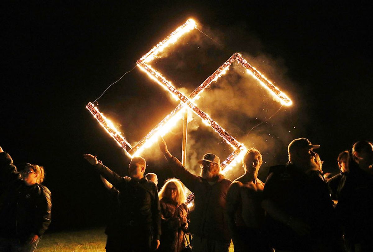Members of the National Socialist Movement, one of the largest neo-Nazi groups in the US, hold a swastika burning after a rally on April 21, 2018 in Draketown, Georgia. Community members had opposed the rally in Newnan and came out to embrace racial unity in the small Georgia town. Fearing a repeat of the violence that broke out after Charlottesville, hundreds of police officers were stationed in the town during the rally in an attempt to keep the anti racist protesters and neo-Nazi groups separated. (Spencer Platt/Getty Images)