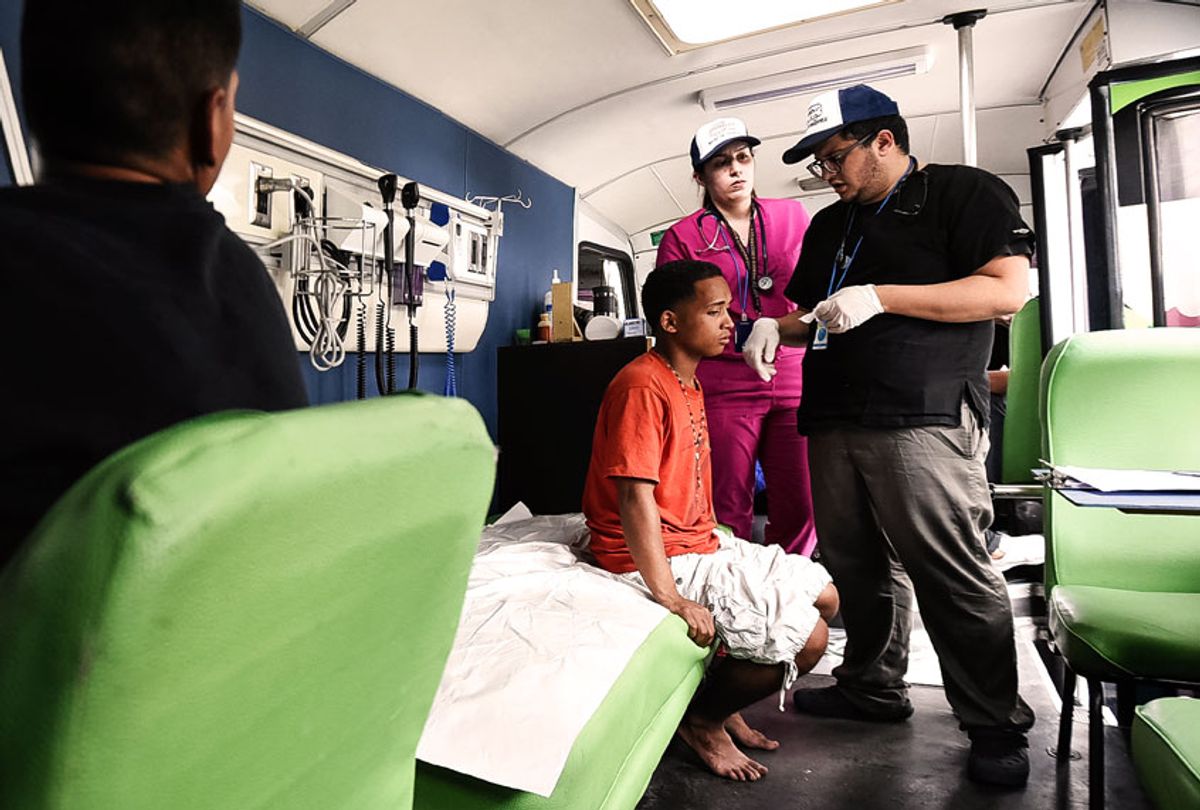 Doctors treat a homeless person suffering from an ear infection on July 25, 2019 in Caracas, Venezuela. Panabus is a network of assistance for homeless people, which seeks to enhance the dignity of those who care for, offering through mobile units the basic services of: personal hygiene, primary medical care and community kitchen. (Carolina Cabral/Getty Images)