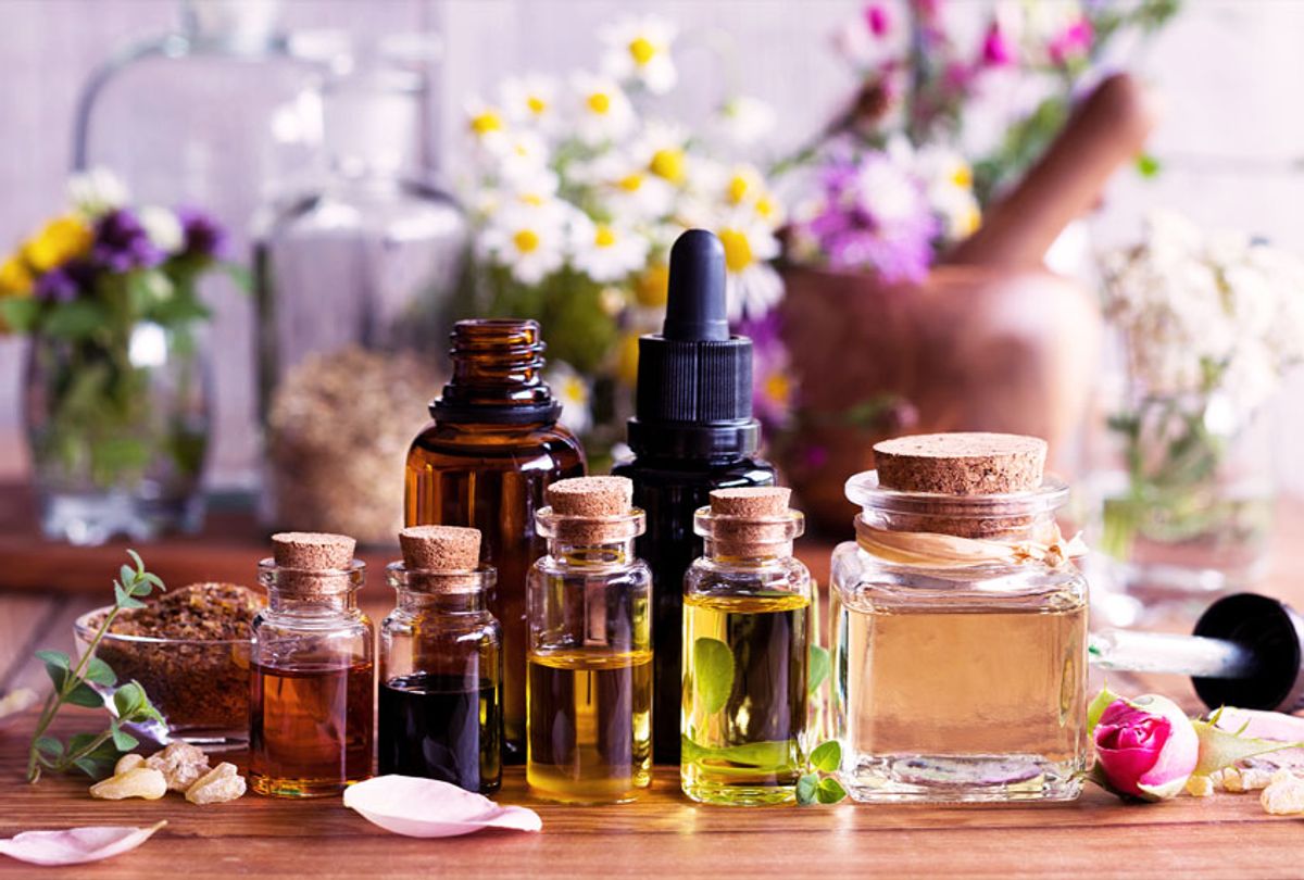 Selection of essential oils with various herbs and flowers in the background (Getty Images/Madeleine Steinbach)