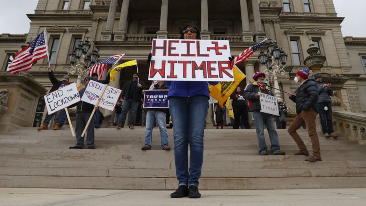 Dawn Perreca protests on the front steps of the Michigan State Capitol building in Lansing, Mich., Wednesday, April 15, 2020. Flag-waving, honking protesters drove past the Michigan Capitol on Wednesday to show their displeasure with Gov. Gretchen Whitmer's orders to keep people at home and businesses locked during the new coronavirus COVID-19 outbreak. (AP Photo/Paul Sancya)