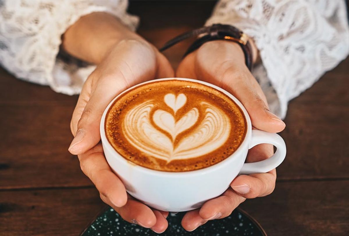 A woman's hands holding a cup of hot latte coffee in her hands (Getty Images)