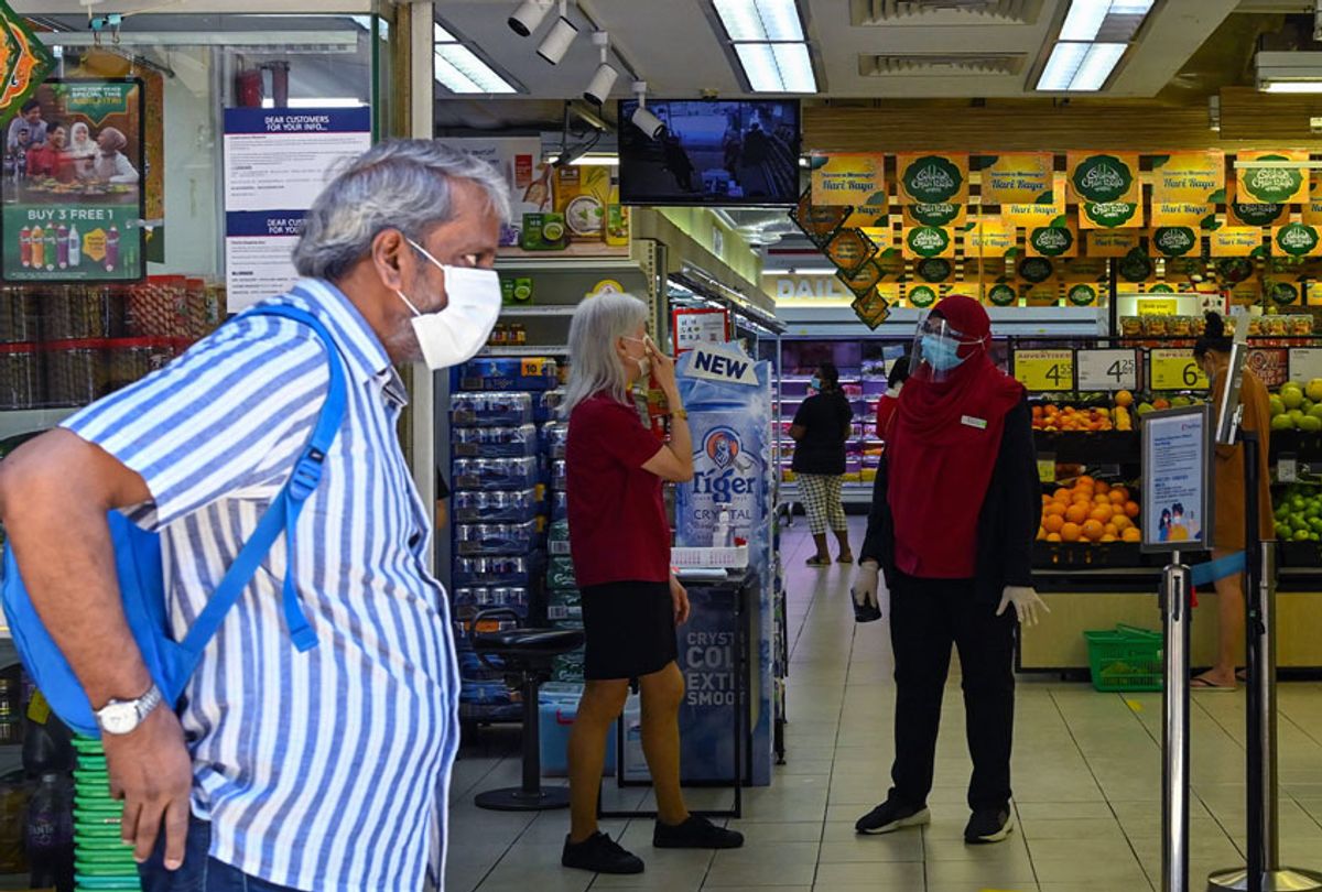 Employees wearing face masks as a preventive measure against the spread of the COVID-19 novel coronavirus stand at the entrance of a supermarket (ROSLAN RAHMAN/AFP via Getty Images)