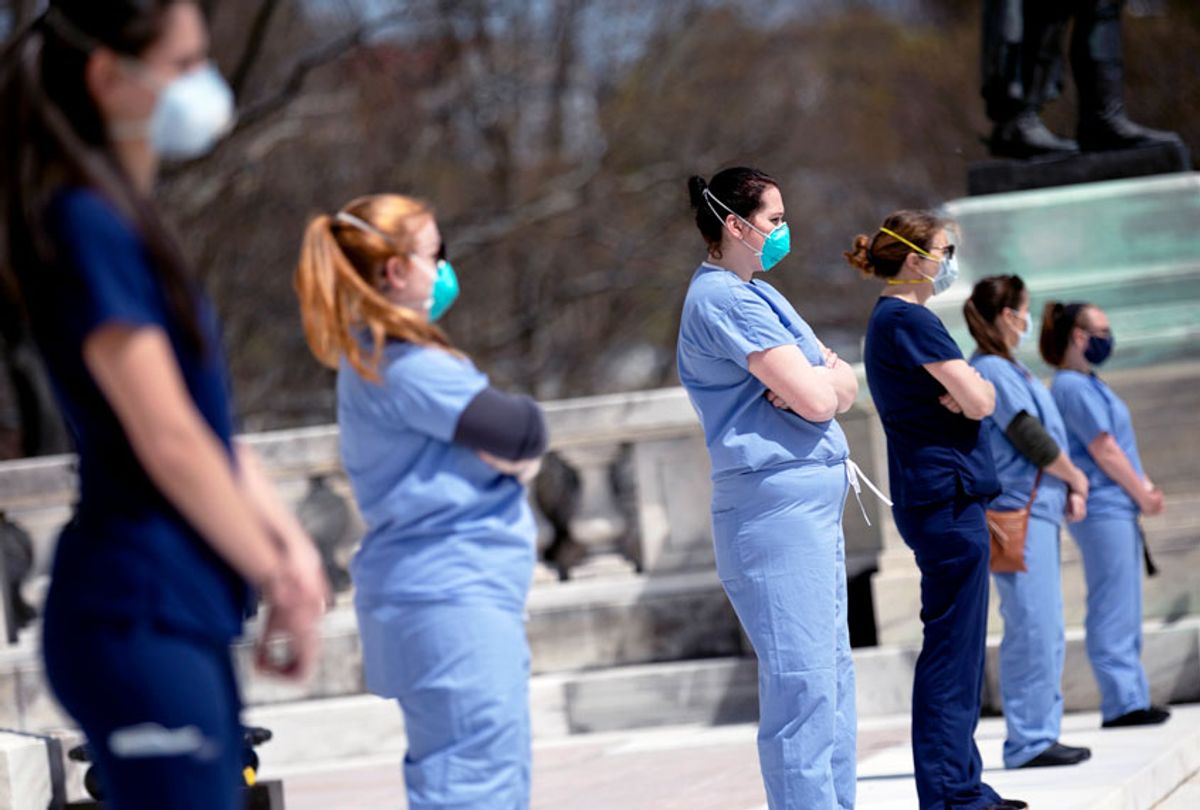 Nurses stand in counter-protest during a demonstration against stay-at-home orders due to coronavirus at the State House (AP Photo/Michael Dwyer)