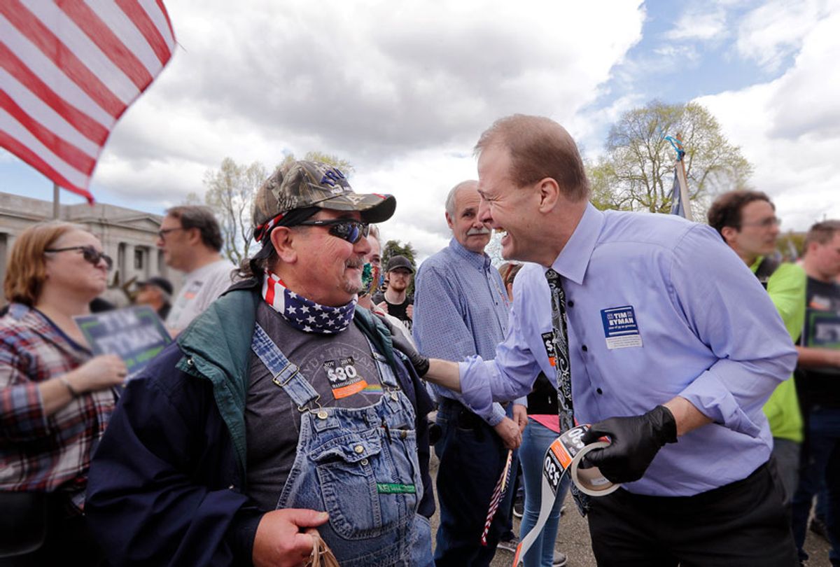 Gubernatorial candidate Tim Eyman, right, disregards social distancing guidelines as he leans in to talk with Chuck Slifko at a crowded protest opposing Washington state's stay-home order to slow the coronavirus outbreak Sunday, April 19, 2020, in Olympia, Wash.  (AP Photo/Elaine Thompson)