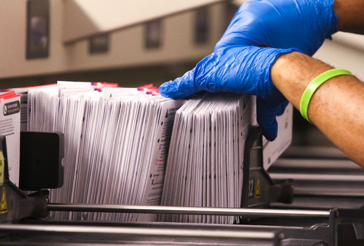 An election worker handles vote-by-mail ballots coming out of a sorting machine  (JASON REDMOND/AFP via Getty Images)