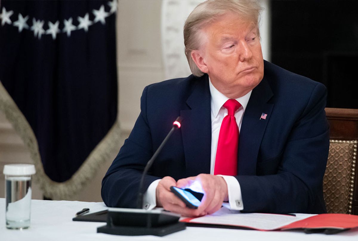 US President Donald Trump uses his cellphone as he holds a roundtable discussion with Governors about the economic reopening of closures due to COVID-19, known as coronavirus, in the State Dining Room of the White House in Washington, DC (SAUL LOEB/AFP via Getty Images)