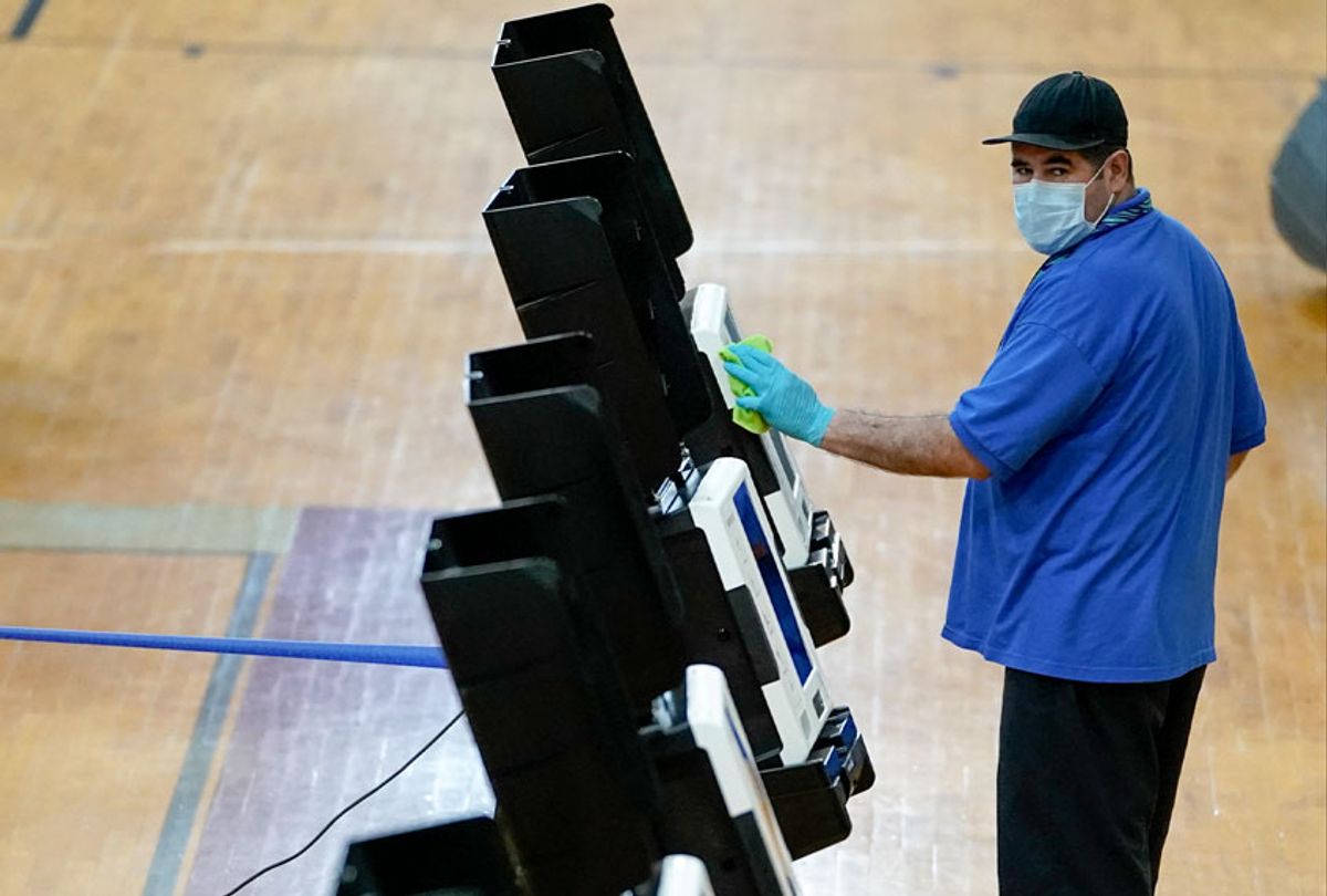 A worker cleans a voting machine after it was used at McKinley Technology High School on primary election day on June 2, 2020 in Washington, DC. On Tuesday, nine states and the District of Columbia are holding primaries, most of which were previously delayed due to the coronavirus pandemic. (Drew Angerer/Getty Images)