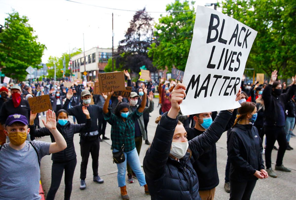 People hold up placards to protest over the death of George Floyd, outside the Seattle Police Department's East Precinct in Seattle, Washington (JASON REDMOND/AFP via Getty Images)