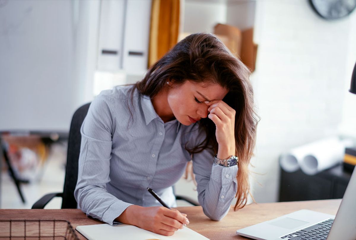 Exhausted businesswoman having a headache at her desk (Getty Images)