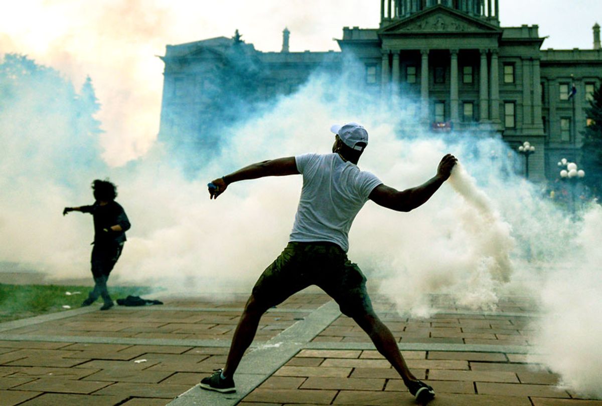 A man throws a tear gas canister back at police officers in front of the Colorado State Capitol as protests against the death of George Floyd continue (Getty Images/Michael Ciaglo)