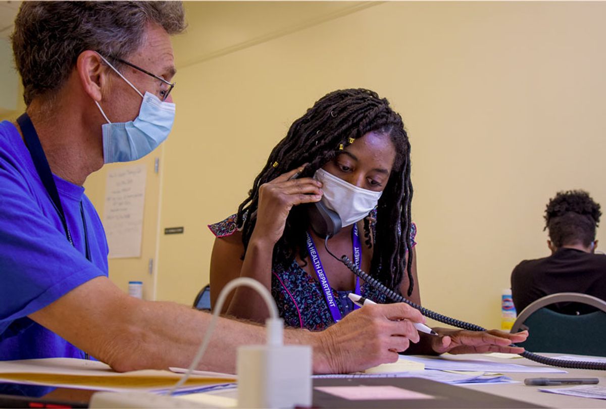 Michael Spatz, L, a volunteer with the Alexandria medical reserve corps, helps AshaLetia Henderson through her first positive-case call as a coronavirus contact tracer, where the Alexandria Health Department set up offices for coronavirus contact tracing and investigations at the Oswald Durant Arts Center in Alexandria, VA, on Wednesday, June 24, 2020. (Jahi Chikwendiu/The Washington Post via Getty Images)