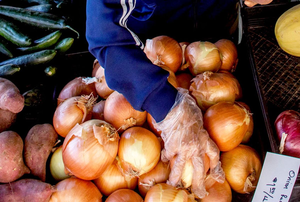 A seller sells onions to a shopper at West LA Farmer's Market in Santa Monica, California on May 3, 2020. - All Farmers Markets in the City of Los Angeles must have an approved COVID-19 operational plan to work under public health orders and Mayor Garcetti's direction. (APU GOMES/AFP via Getty Images)