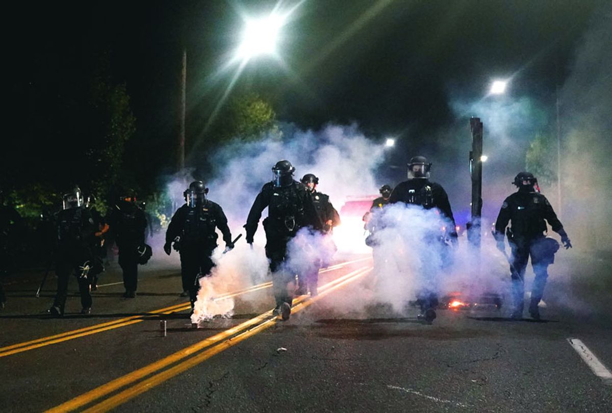 Portland police officers walk through clouds of smoke while dispersing a crowd from in front of the Multnomah County Sheriffs Office on August 22, 2020 in Portland, Oregon. Hundreds of protesters clashed with police Saturday night following a rally in east Portland. (Nathan Howard/Getty Images)