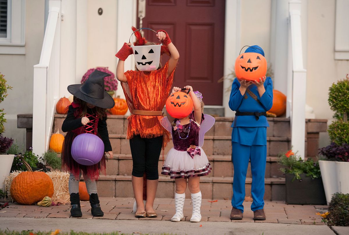 Children covering face with Jack O Lantern bucket in front of house (Getty Images)