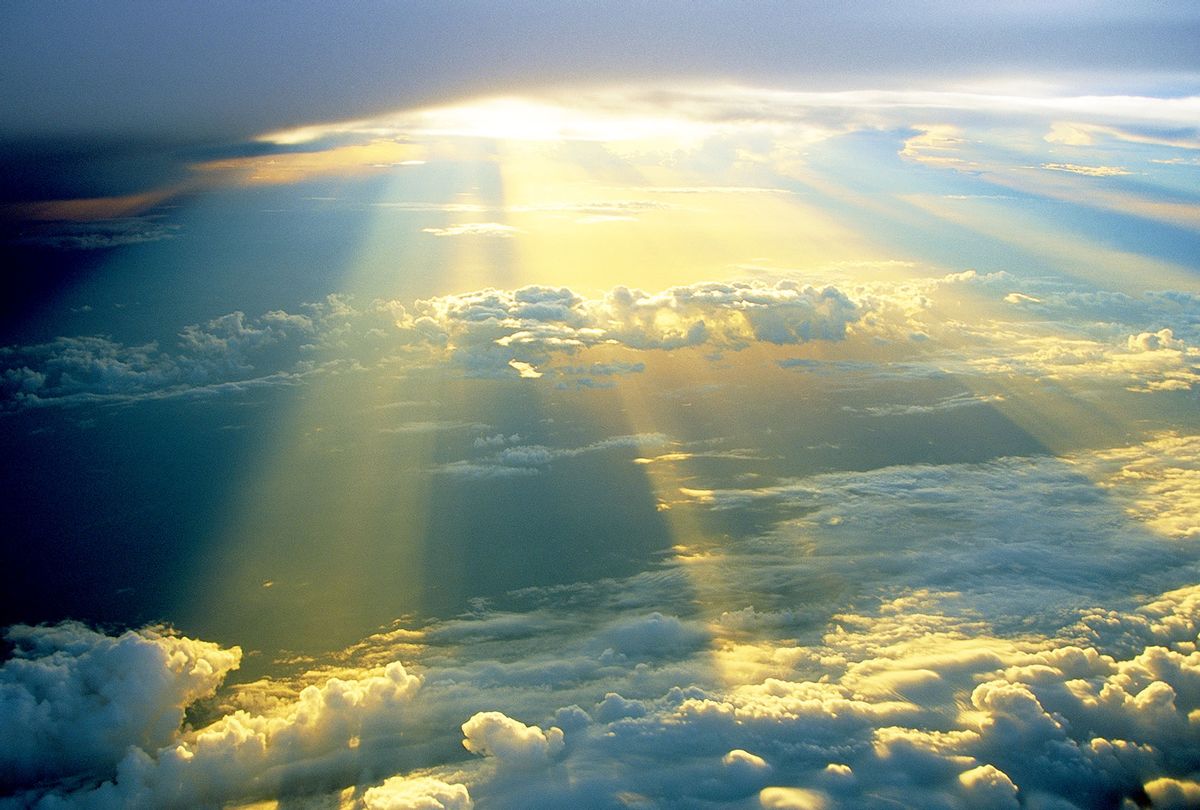 Golden sun rays beaming through white clouds (Getty Images)