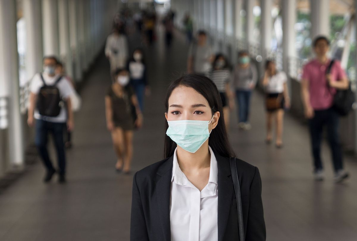 Woman with protective face mask in the urban bridge in city against crowd of peopl (Getty Images)