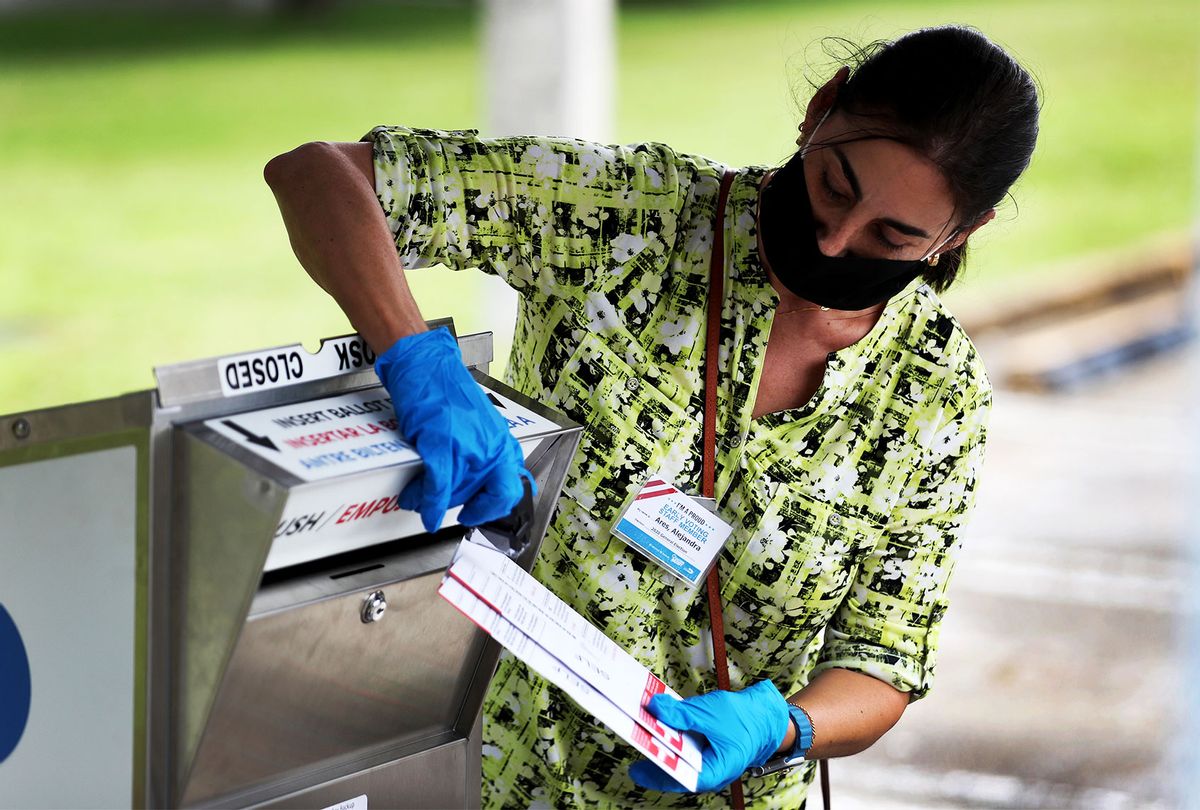 A poll worker places Vote-by-Mail ballots into an official ballot drop box setup at the Election Headquarters polling station on October 19, 2020 in Doral, Florida. (ROBYN BECK/AFP via Getty Images)