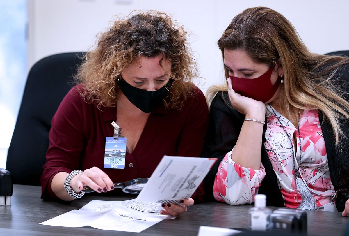 Milena Abreu, County Judge, and Victoria Ferrer, County Judge, inspect a Vote-by-Mail ballot for a valid signature as Miami-Dade County Canvassing Board convenes ahead of the November 3rd general election at the Miami-Dade County Elections Department on October 15, 2020 in Doral, Florida. (Joe Raedle/Getty Images)
