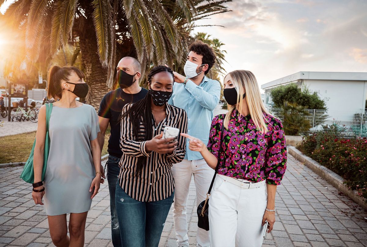 Group of friends meeting in the city wearing protective face masks (Getty Images)