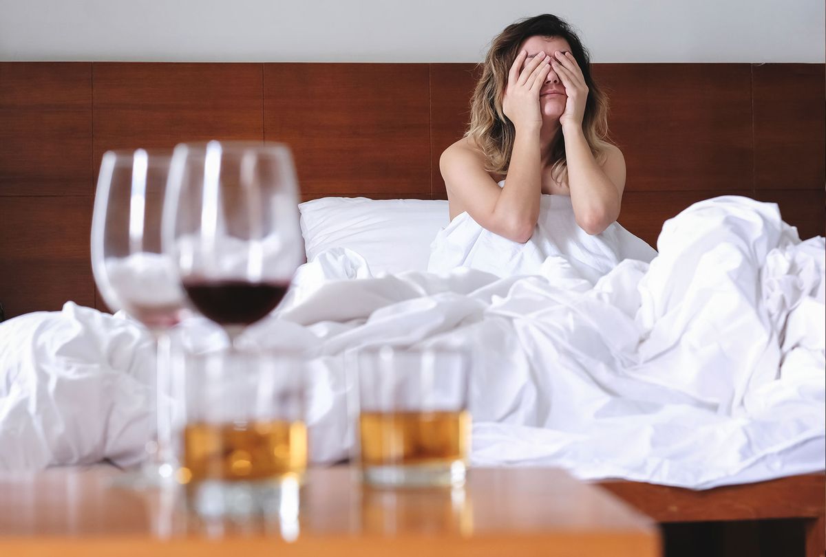Young exhausted and wasted woman waking up suffering headache and hangover after drinking alcohol lying on bed sick and miserable still drunk (Getty Images)