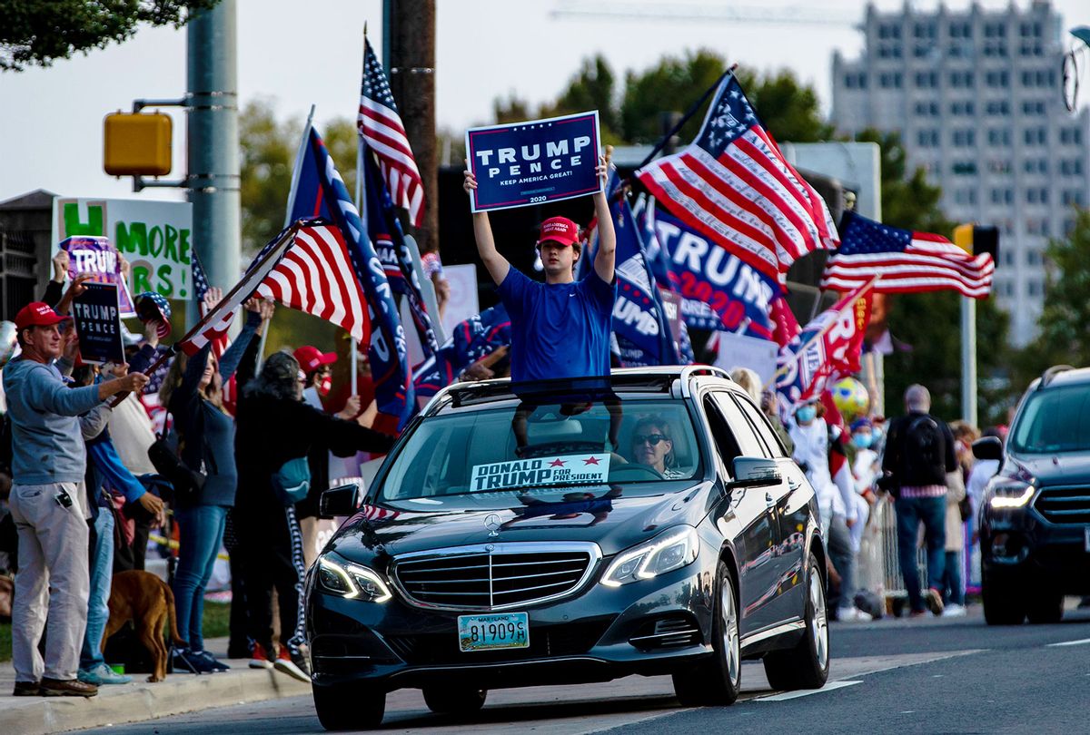 A supporter of President Donald Trump holds a campaign sign through the moonroof of a car as they drive past Walter Reed National Military Medical Center after the President was admitted for treatment of COVID-19 on October 4, 2020 in Bethesda, Maryland. (Samuel Corum/Getty Images)