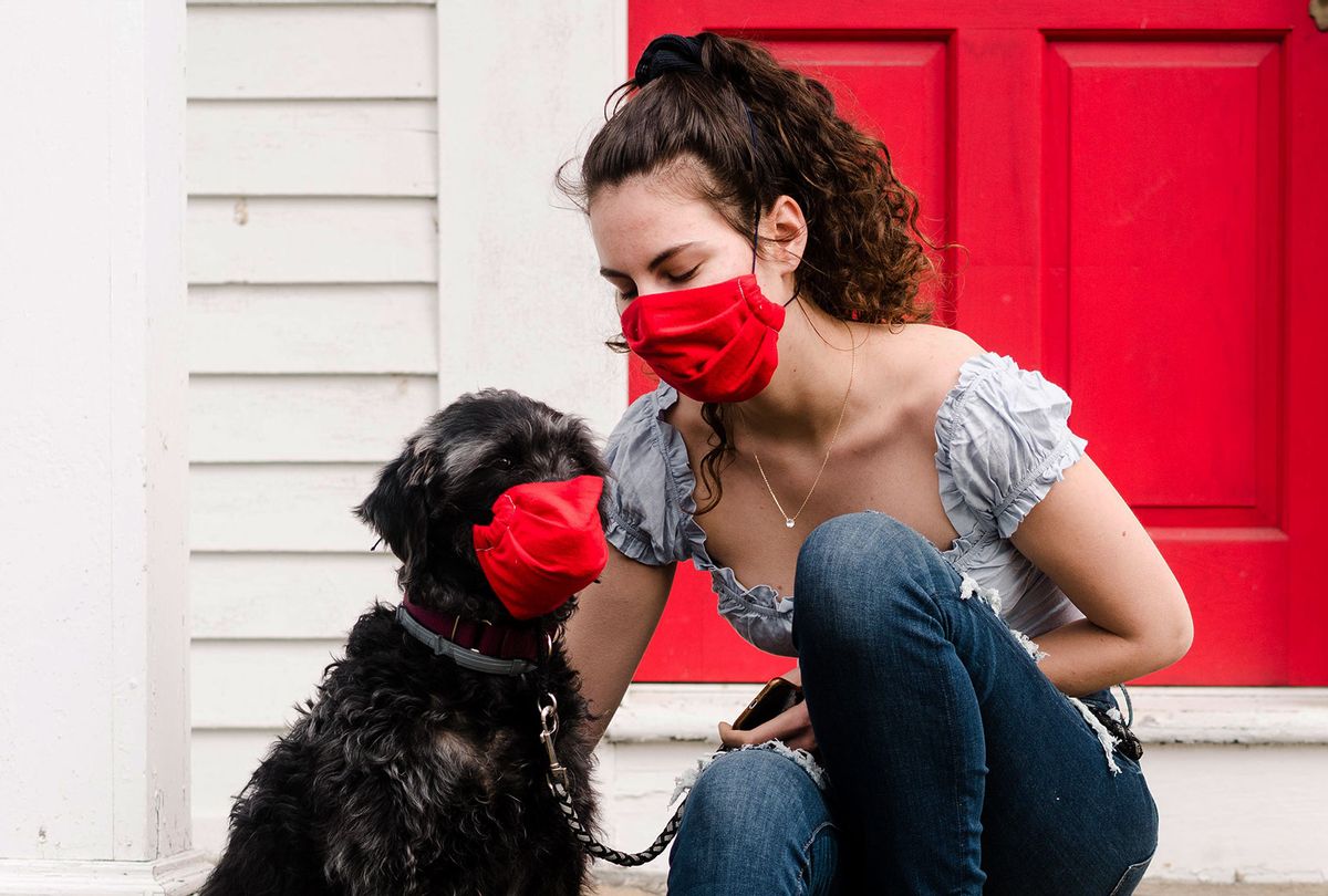 Young woman and dog wearing read mask during COVID-19 pandemic (Getty Images)
