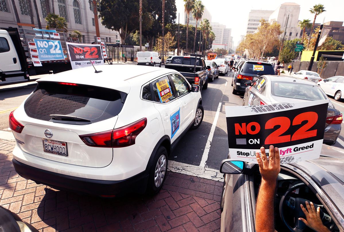 Rideshare driver Jorge Vargas raises his No on 22 sign in support as app based gig workers held a driving demonstration with 60-70 vehicles blocking Spring Street in front of Los Angeles City Hall urging voters to vote no on Proposition 22, a November ballot measure that would classify app-based drivers as independent contractors and not employees or agents, providing them with an exemption from Californias AB 5. (Al Seib / Los Angeles Times)