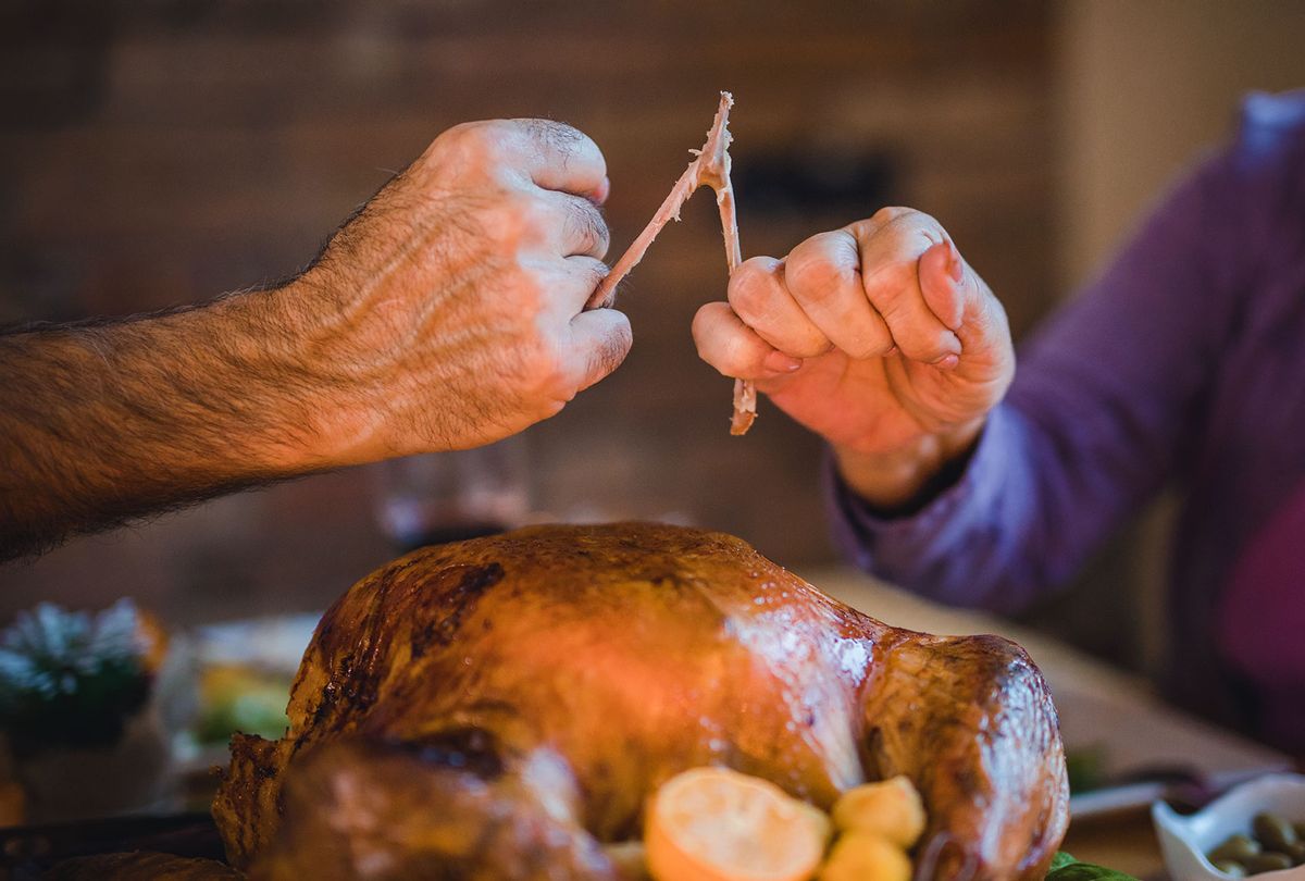 People pulling wishbone during Thanksgiving dinner. (Getty Images)