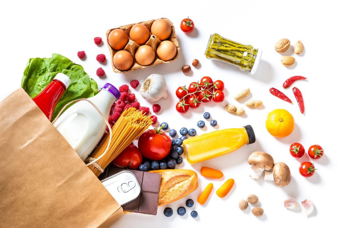 Top view of a paper bag full of canned food, fruits, vegetables, eggs, a milk bottle, berries, mushrooms, nuts, pasta, a chocolate bar and bread.  (Getty Images)