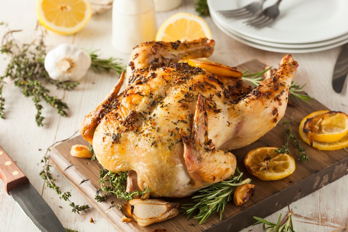 Lemon and herb whole chicken on wooden board (Getty Images)