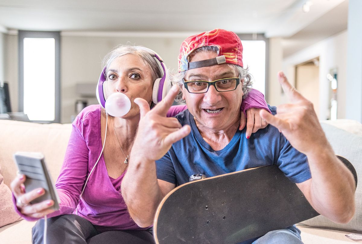 Young at heart grandparents listening to music and flashing the rock sign (Getty Images)