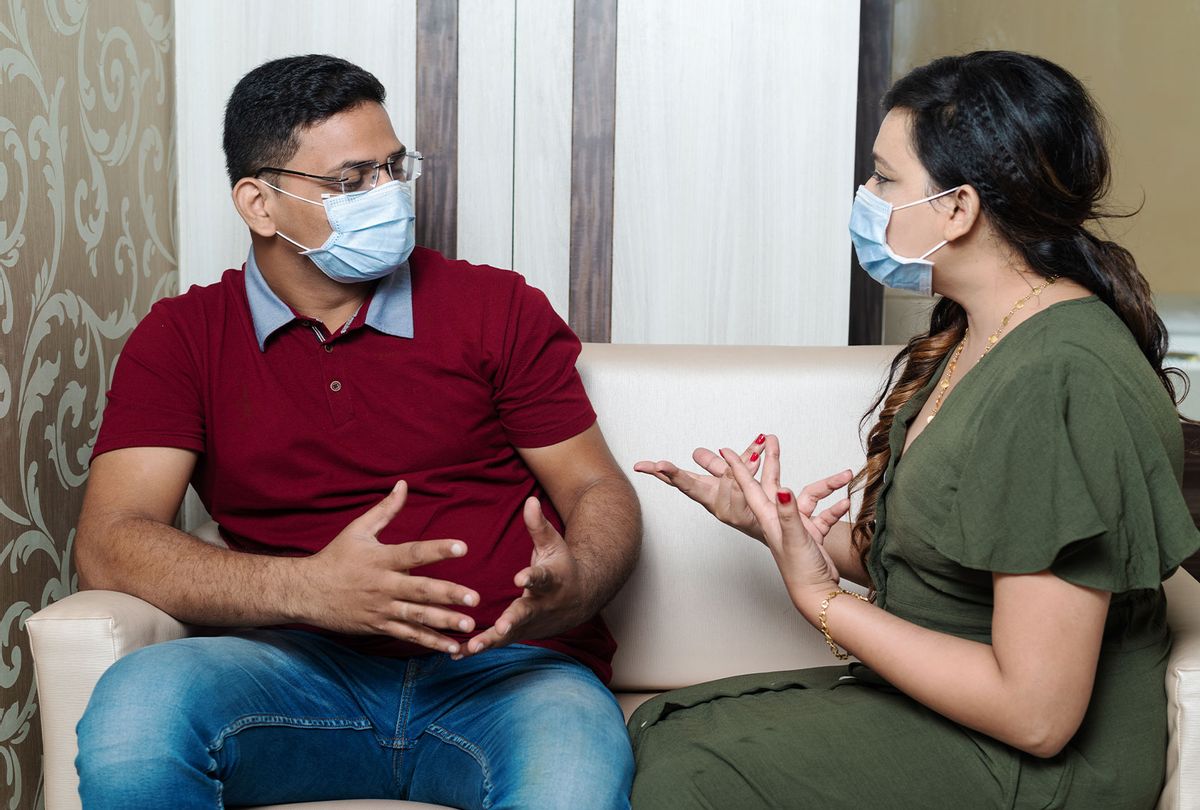 Young couple in medical masks quarreling (Getty Images)