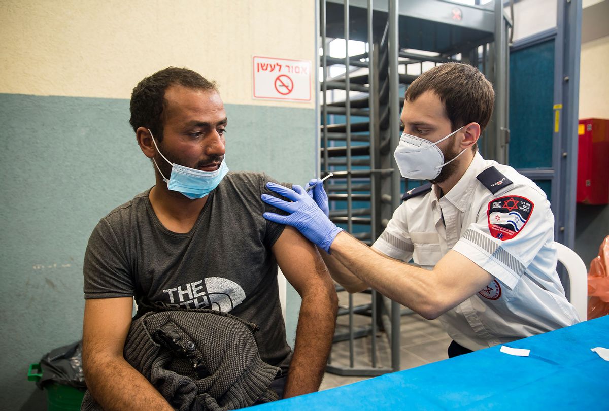 A Palestinian man who works in Israel receives the first dose of a Moderna Covid-19 vaccine by an Israeli medical worker in Meitar crossing checkpoint between the West bank and Israel on March 9, 2021 in Meitar, Israel. More than two months after starting a world-leading covid-19 vaccination campaign for its own citizens, Israel began administering the Moderna vaccine to Palestinian laborers from the West Bank who enter Israel or Israeli settlements for work. More than 100,000 Palestinians work in the country and its settlements. (Amir Levy/Getty Images)