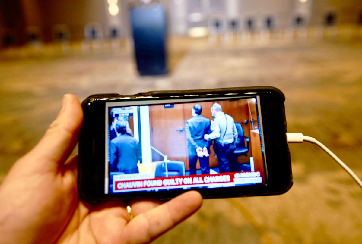 A journalist watches their mobile phone showing Derek Chauvin taking back into custody after the verdict in his trial over the death of George Floyd has been announced in Minneapolis, Minnesota on April 20, 2021. - Sacked police officer Derek Chauvin was convicted of murder and manslaughter on april 20 in the death of African-American George Floyd in a case that roiled the United States for almost a year, laying bare deep racial divisions. (KEREM YUCEL/AFP via Getty Images)