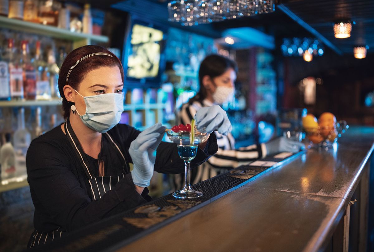 Bartender women working with protective face mask and surgical gloves in night bar. (Getty Images)