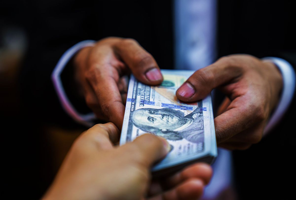 Businessman giving bribe money to partner (Getty Images)