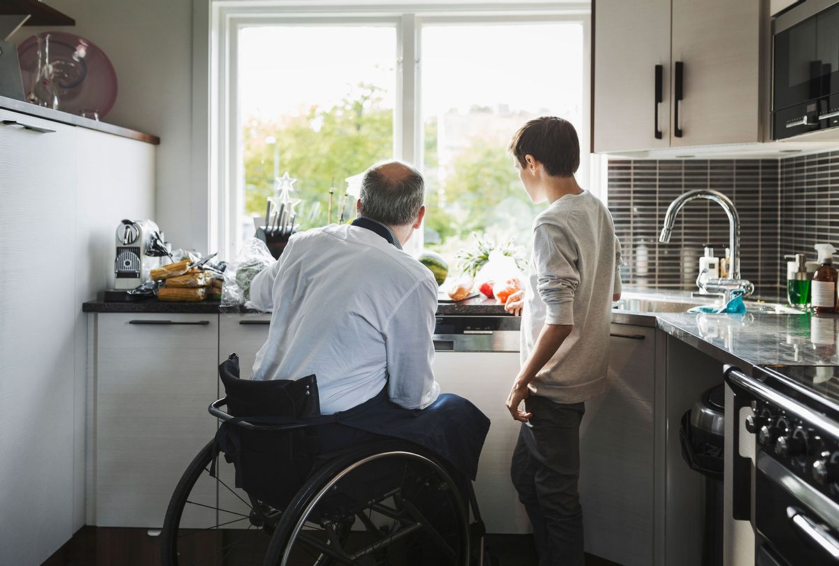 Disabled father preparing food with son in the kitchen (Getty Images)