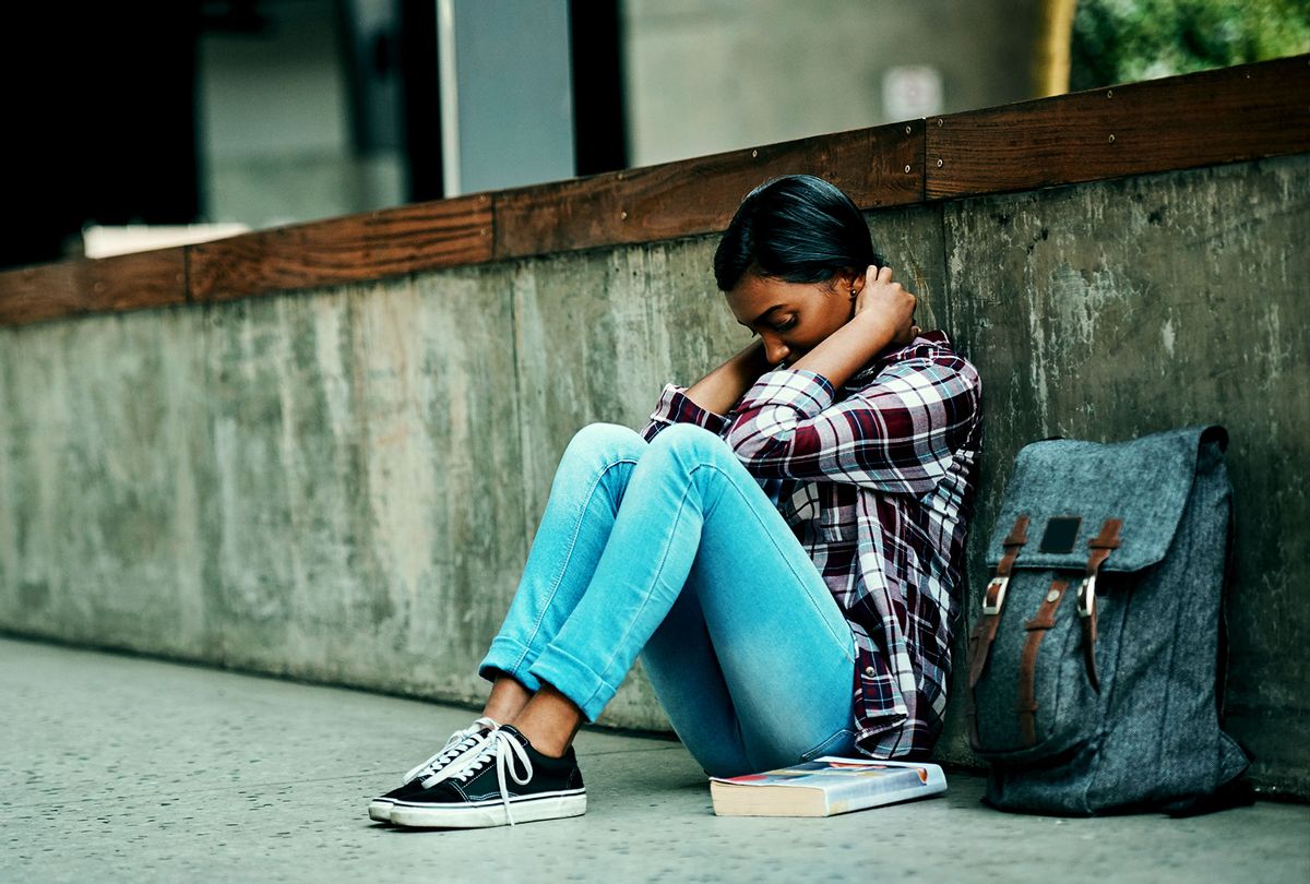 Stressed college student hiding behind a wall (Getty Images)