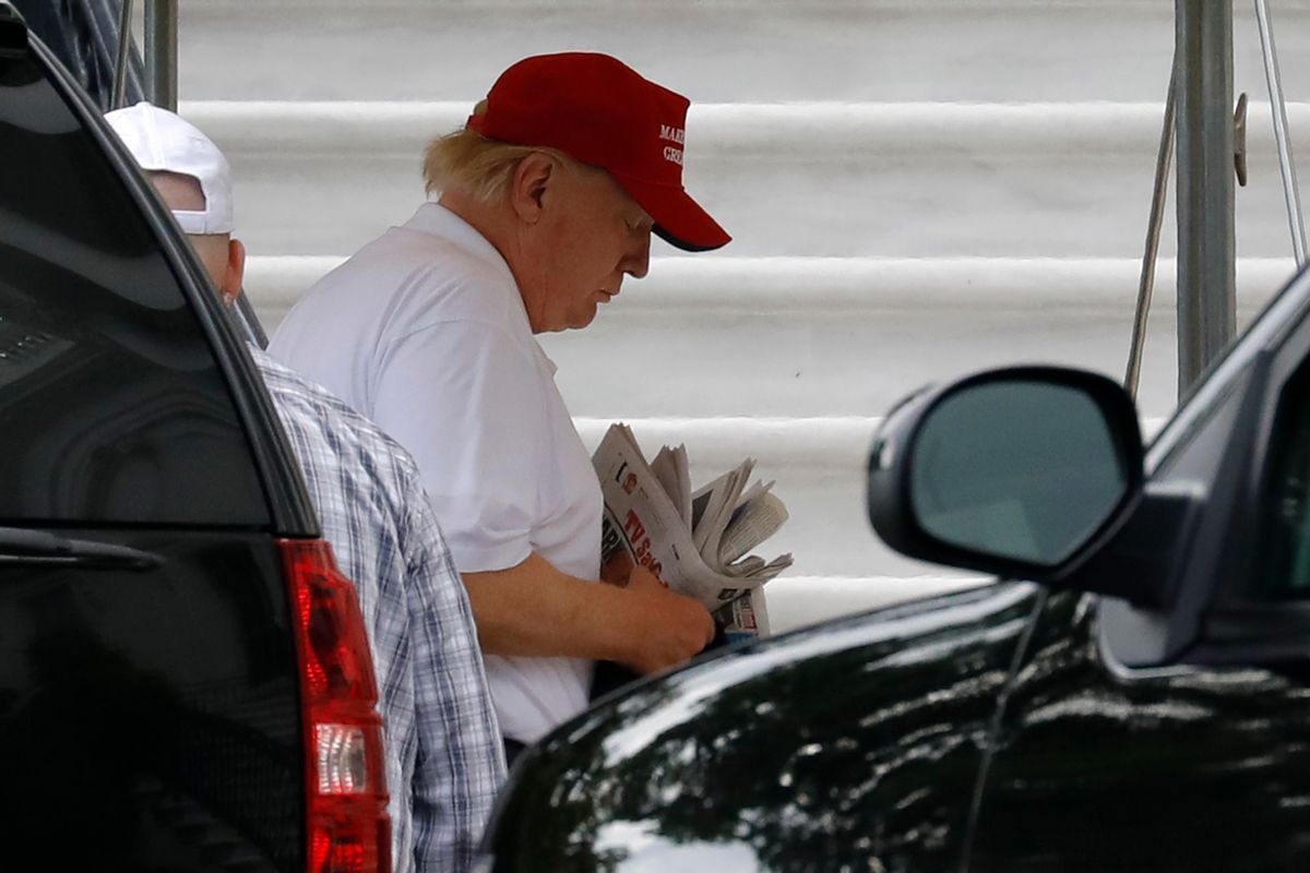 Former President Donald Trump thumbs through a stack of newspapers. (Getty Images)