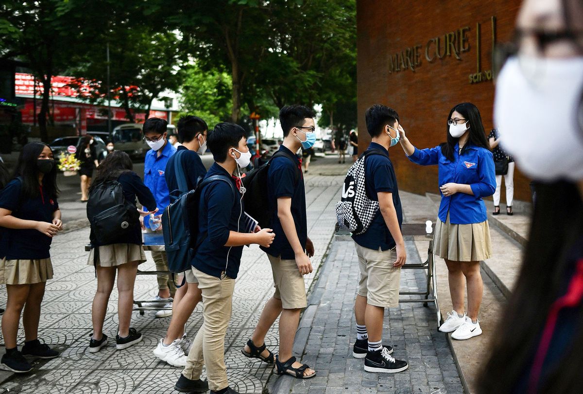 Students wearing face masks stand in a queue to get their temperatures checked at the Marie Curie school in Hanoi on May 4, 2020, as schools re-opened after a three-month closure to combat the spread of the COVID-19 novel coronavirus. (MANAN VATSYAYANA/AFP via Getty Images)
