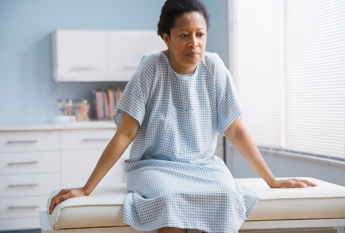 Woman patient sitting on examination table in doctor's office (Getty Images)