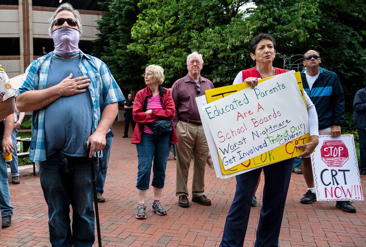People hold up signs during a rally against "critical race theory" (CRT) being taught in schools at the Loudoun County Government center in Leesburg, Virginia on June 12, 2021. The term "critical race theory" defines a strand of thought that appeared in American law schools in the late 1970s and which looks at racism as a system, enabled by laws and institutions, rather than at the level of individual prejudices. But critics use it as a catch-all phrase that attacks teachers' efforts to confront dark episodes in American history, including slavery and segregation, as well as to tackle racist stereotypes. (ANDREW CABALLERO-REYNOLDS/AFP via Getty Images)
