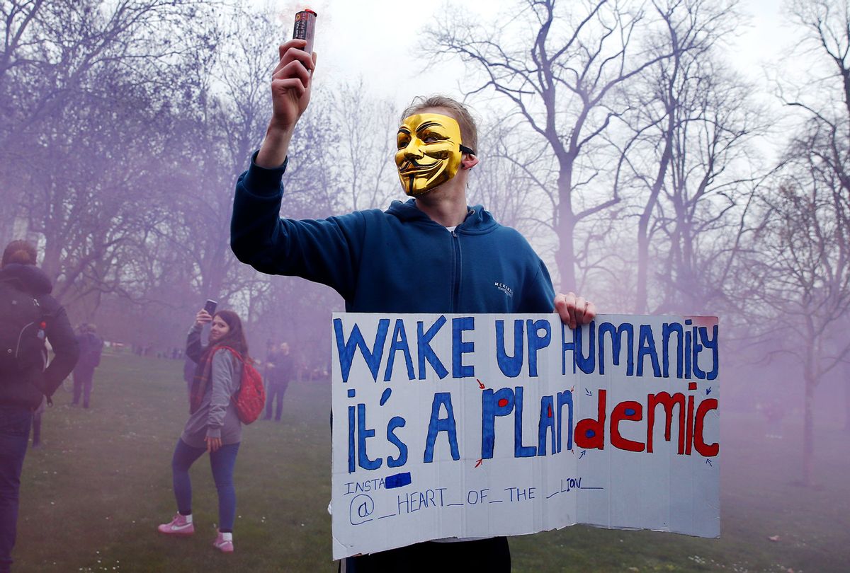 A protester with a flare poses holding a sign calling for people to "wake up" during a "World Wide Rally For Freedom" protest, a QAnon adjacent conspiracy-theory movement. (Hollie Adams/Getty Images)
