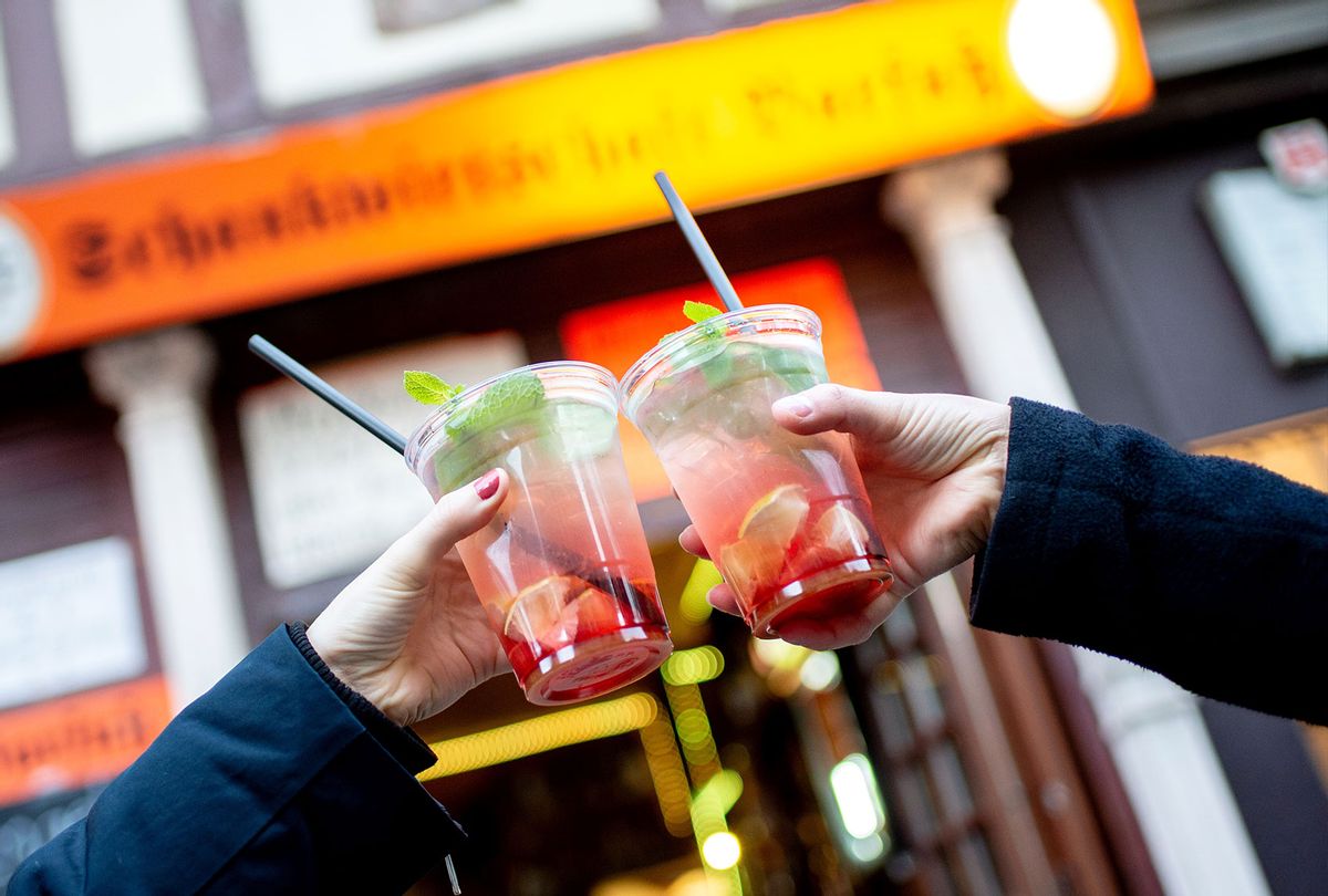Two friends toast with to-go strawberry mojitos in front of a bar. (Hauke-Christian Dittrich/picture alliance via Getty Images)