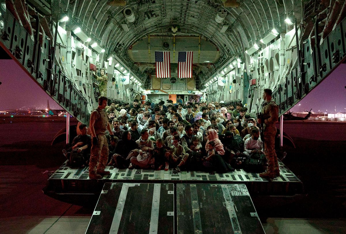 In this handout provided by the U.S. Air Force, an air crew assigned to the 816th Expeditionary Airlift Squadron assists evacuees aboard a C-17 Globemaster III aircraft in support of the Afghanistan evacuation at Hamid Karzai International Airport on August 21, 2021 in Kabul, Afghanistan. (Taylor Crul/U.S. Air Force via Getty Images)