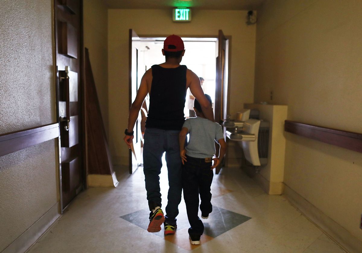 A man walks with his son after being reunited in an I.C.E processing center, after being separated for three months when they tried to cross into the United States. (Joe Raedle/Getty Images)