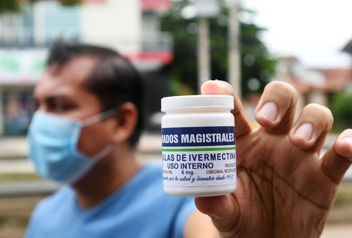 A man with a mouth guard shows a can of ivermectin capsules as he comes out of the pharmacy. (Rodrigo Urzagasti/picture alliance via Getty Images)