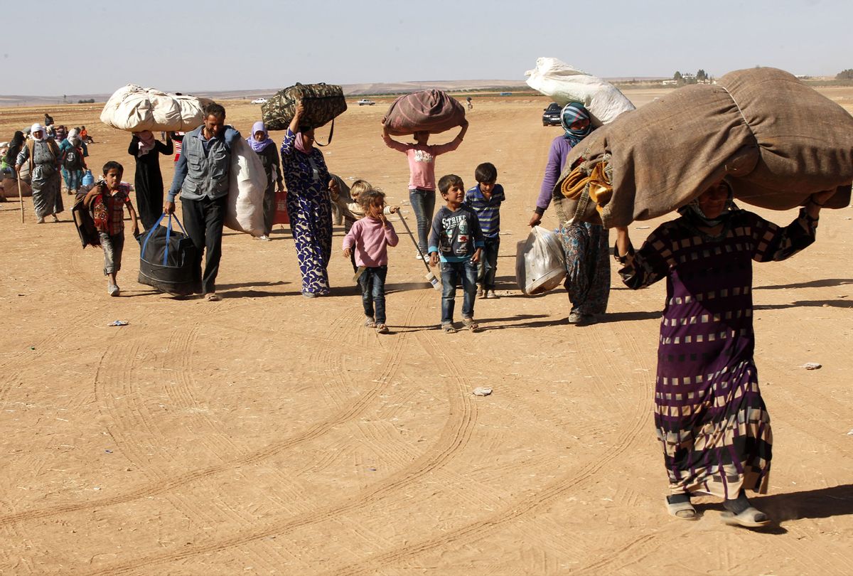 Syrian Kurdish refugees walk with their belongings after crossing into Turkey from the Syrian border town of Kobani on September 26, 2014 near the southeastern town of Suruc in Sanliurfa province, Turkey. (Stringer/Getty Images)
