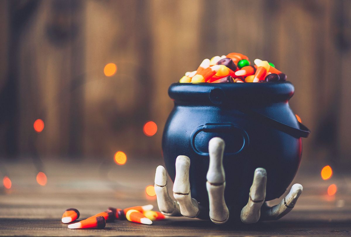 Skeletal hand holding cauldron with candy (Getty Images/CatLane)